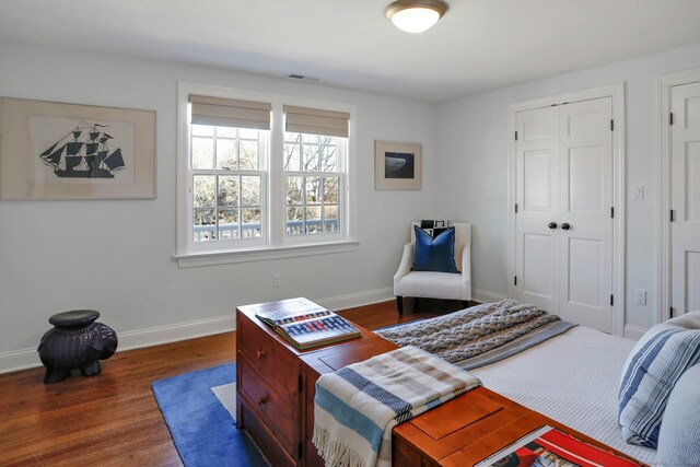 bedroom featuring a closet, visible vents, baseboards, and wood finished floors