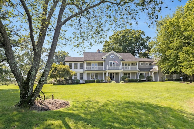 view of front of house featuring a front lawn, a chimney, and a balcony