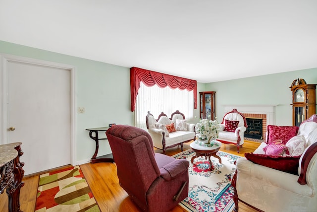 living area featuring a fireplace, light wood-type flooring, and baseboards