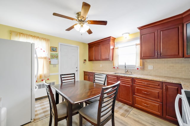 kitchen featuring light wood-type flooring, a sink, freestanding refrigerator, decorative backsplash, and stove