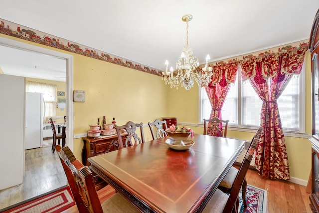 dining area featuring baseboards, an inviting chandelier, and light wood finished floors