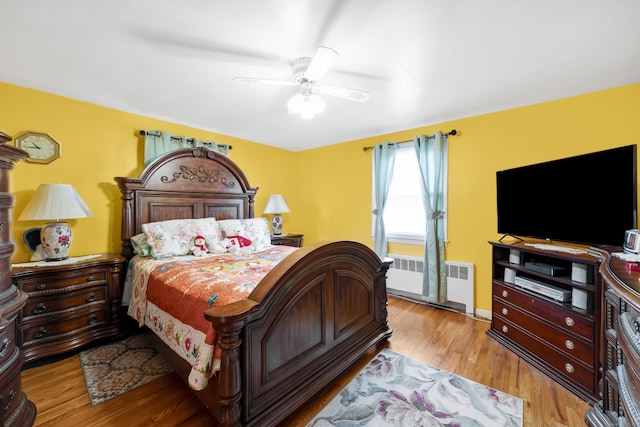 bedroom with radiator, baseboards, light wood-type flooring, and ceiling fan