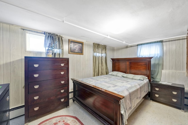 bedroom with a baseboard heating unit and wood walls