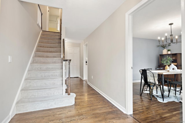 staircase featuring a chandelier, wood finished floors, and baseboards