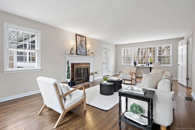 living room featuring a fireplace, wood finished floors, visible vents, and baseboards