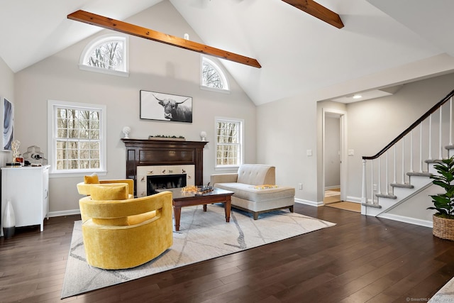 living area featuring wood-type flooring, a fireplace, beam ceiling, and stairs