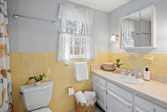 bathroom featuring plenty of natural light, vanity, toilet, and tile walls