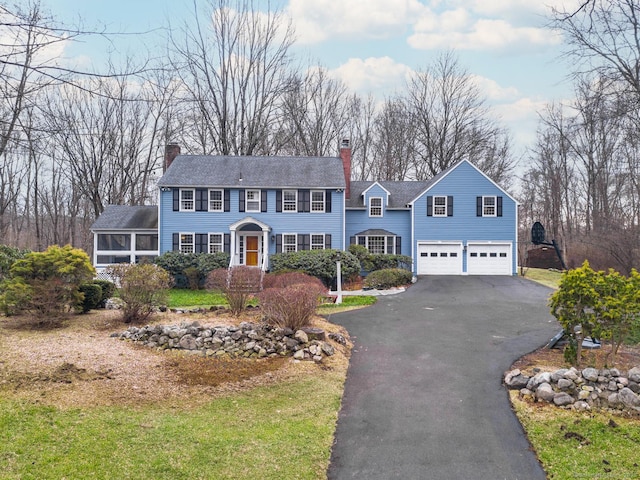 view of front of property featuring aphalt driveway, a chimney, and a garage