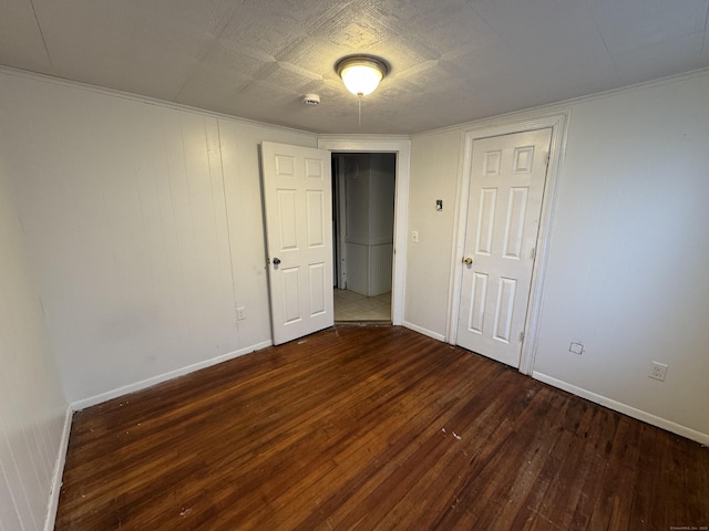 spare room featuring crown molding, baseboards, and hardwood / wood-style floors