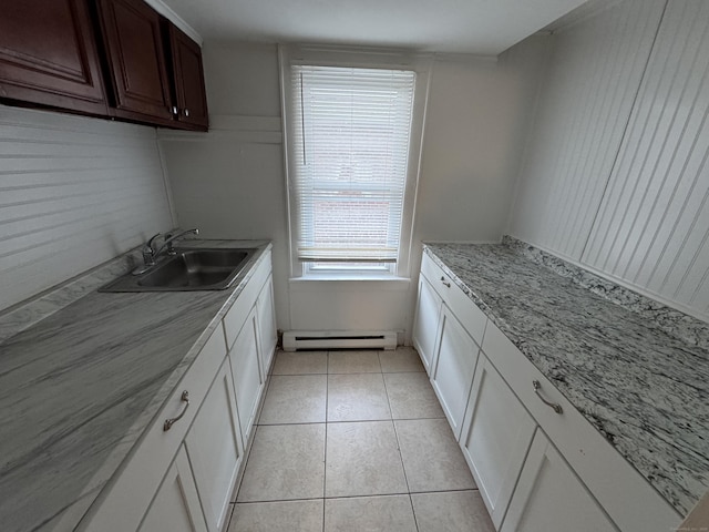 kitchen with a baseboard radiator, white cabinets, a sink, and light tile patterned floors