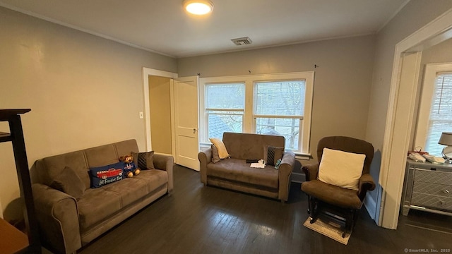 living area with crown molding, visible vents, and wood finished floors