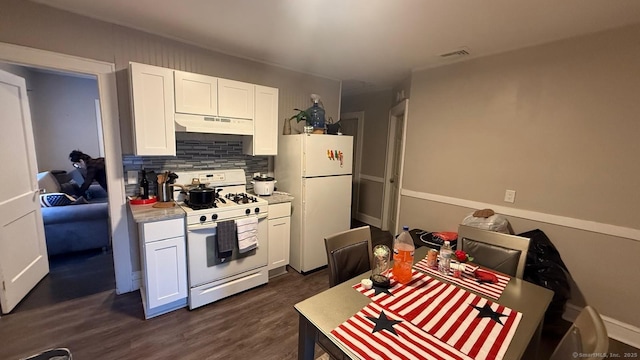 kitchen with white appliances, white cabinets, dark wood finished floors, light countertops, and under cabinet range hood