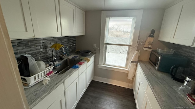 kitchen with a wealth of natural light, tasteful backsplash, white cabinetry, and a sink