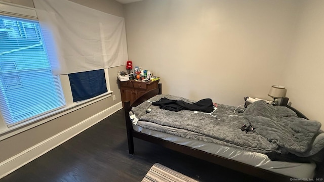 bedroom with dark wood finished floors and baseboards