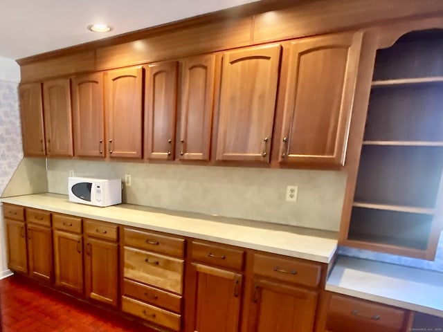 kitchen featuring brown cabinets, white microwave, light countertops, and recessed lighting