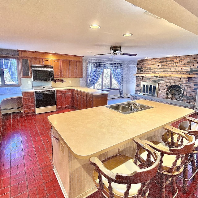 kitchen featuring brick floor, white range, light countertops, a brick fireplace, and cooktop