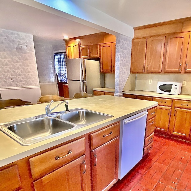 kitchen featuring white microwave, a sink, light countertops, freestanding refrigerator, and dishwasher