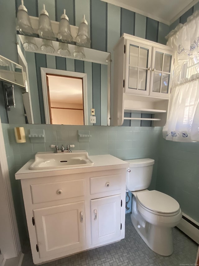 bathroom with tile walls, toilet, baseboard heating, vanity, and tile patterned floors