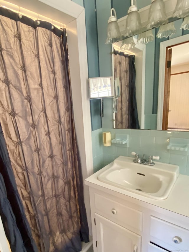 full bathroom with tasteful backsplash, curtained shower, and vanity