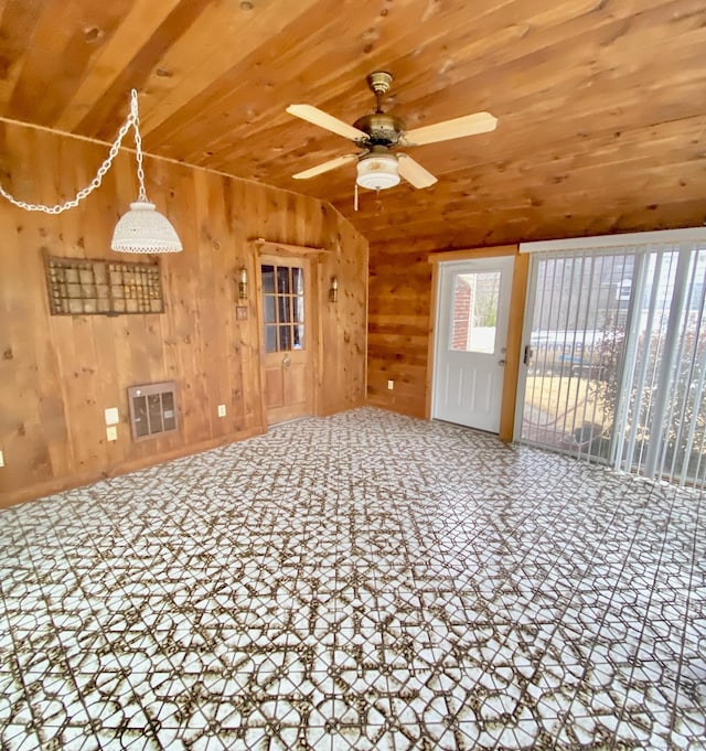 unfurnished living room with wooden walls, visible vents, a ceiling fan, wooden ceiling, and vaulted ceiling