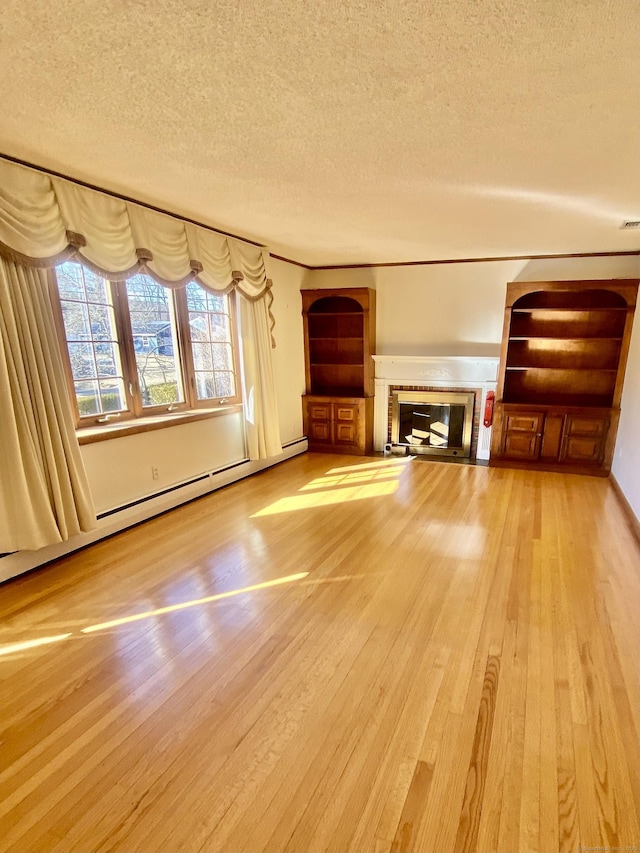 unfurnished living room featuring a textured ceiling, baseboard heating, a glass covered fireplace, and light wood-style flooring