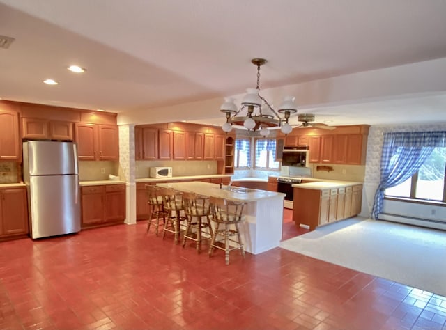 kitchen featuring white microwave, freestanding refrigerator, a kitchen island with sink, light countertops, and recessed lighting