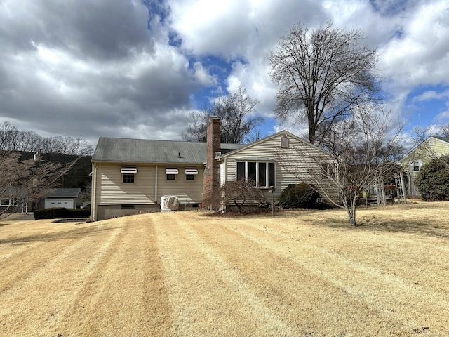 back of house featuring crawl space, dirt driveway, a chimney, and a lawn