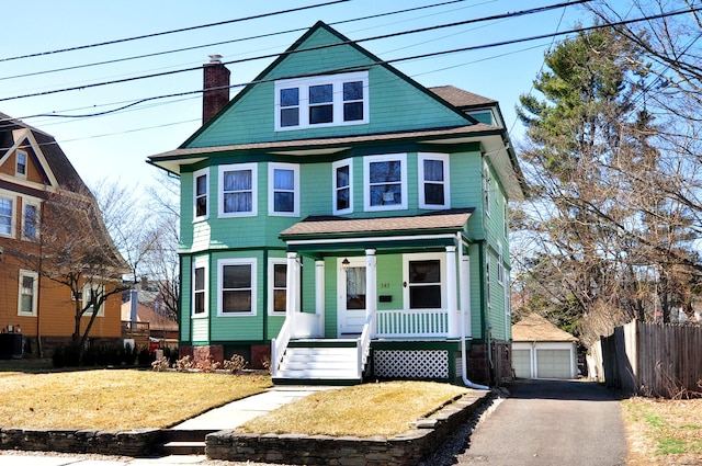 view of front of home with a front lawn, fence, covered porch, a chimney, and an outdoor structure