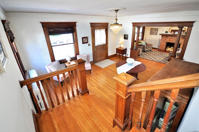 interior space featuring a brick fireplace, an inviting chandelier, radiator heating unit, and light wood finished floors