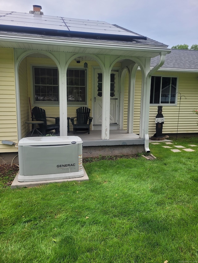 back of house with a porch, roof mounted solar panels, and a yard