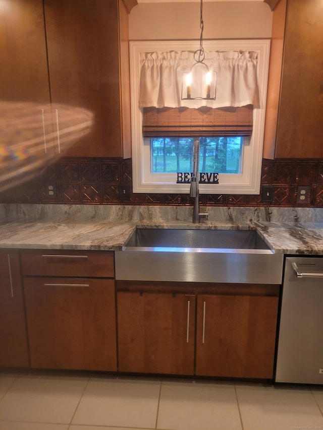 kitchen featuring a sink, backsplash, stainless steel dishwasher, and light tile patterned floors