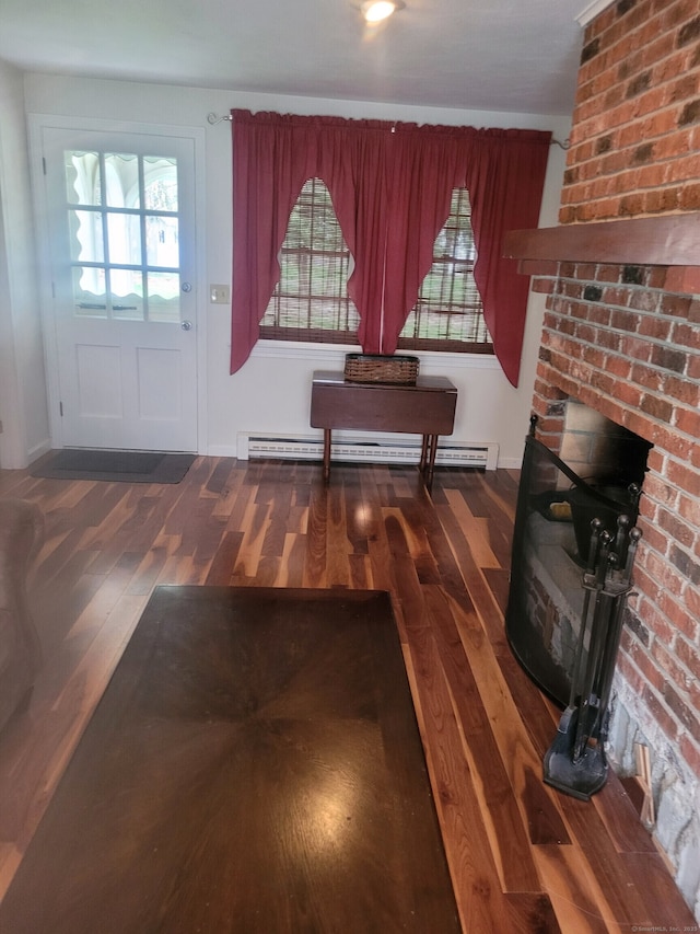 interior space featuring a fireplace, a baseboard heating unit, and wood finished floors