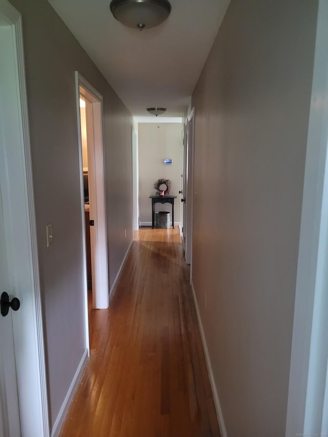 corridor featuring hardwood / wood-style flooring and baseboards