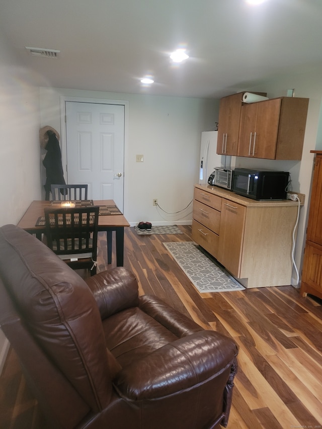 living room featuring baseboards, visible vents, and wood finished floors