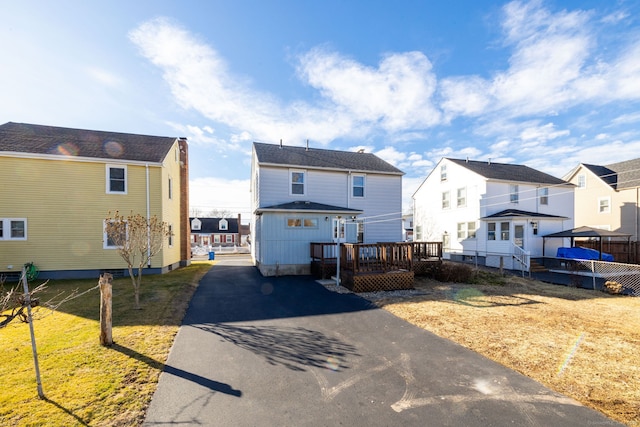 view of front of house featuring a wooden deck, a residential view, a front yard, and driveway