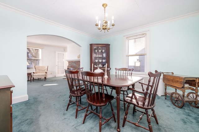 dining area with arched walkways, carpet, an inviting chandelier, crown molding, and baseboards