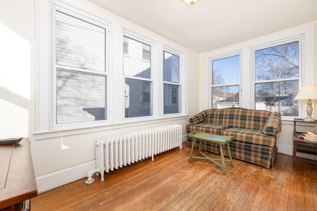 living area with baseboards, radiator, and hardwood / wood-style flooring