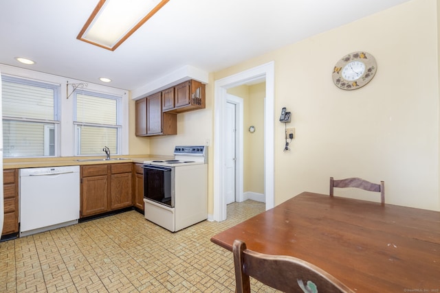 kitchen with white appliances, brown cabinetry, recessed lighting, a sink, and light countertops