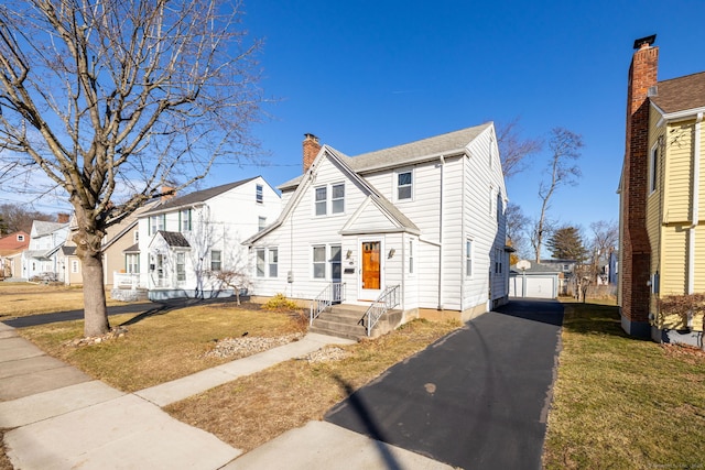 view of front of home featuring a residential view, driveway, a front lawn, and an outdoor structure