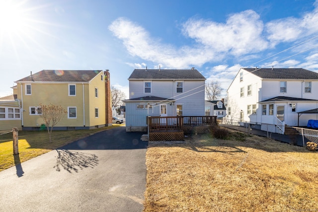 view of front of property with aphalt driveway, a deck, and a front lawn