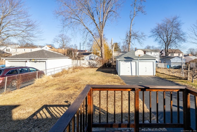 view of yard with a residential view, a detached garage, an outdoor structure, and fence