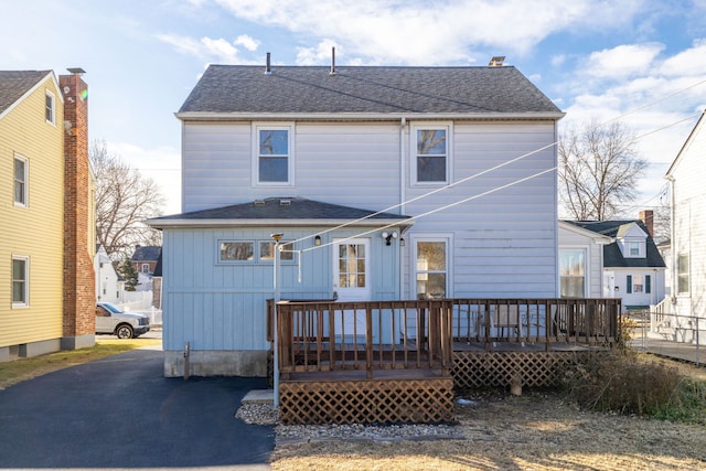 rear view of property featuring a deck and roof with shingles