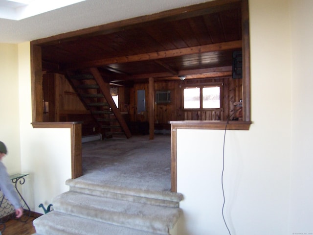 stairway with wood ceiling, carpet flooring, wood walls, electric panel, and beamed ceiling