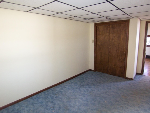 unfurnished bedroom with carpet, a paneled ceiling, and baseboards