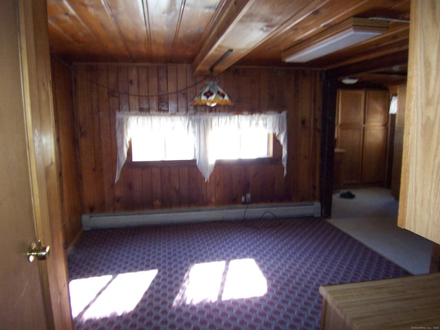 carpeted empty room featuring wood walls, baseboard heating, and wooden ceiling