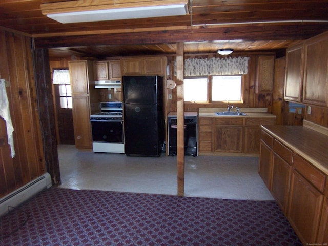 kitchen with a baseboard radiator, a sink, wooden walls, under cabinet range hood, and black appliances