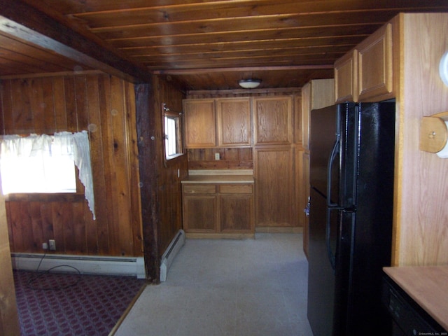 kitchen featuring freestanding refrigerator, wood walls, and a baseboard radiator