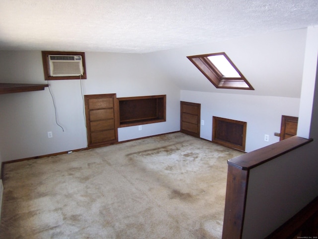 bonus room featuring carpet floors, vaulted ceiling with skylight, a wall unit AC, and a textured ceiling