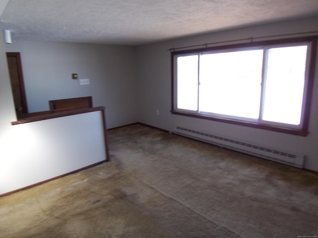 carpeted empty room featuring a baseboard radiator and a textured ceiling