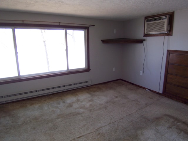 spare room with a baseboard heating unit, a textured ceiling, a wall mounted air conditioner, and carpet